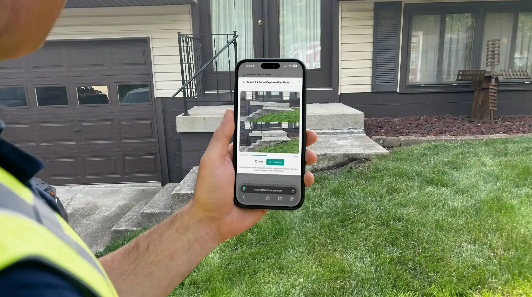 Before and After Creator In CRM Software After Taking Before and After Photo With Ghosted Overlay Gone — contractor in a safety vest holding a smartphone showing the ContractorCore before and after capture screen on a job site with a residential home in the background